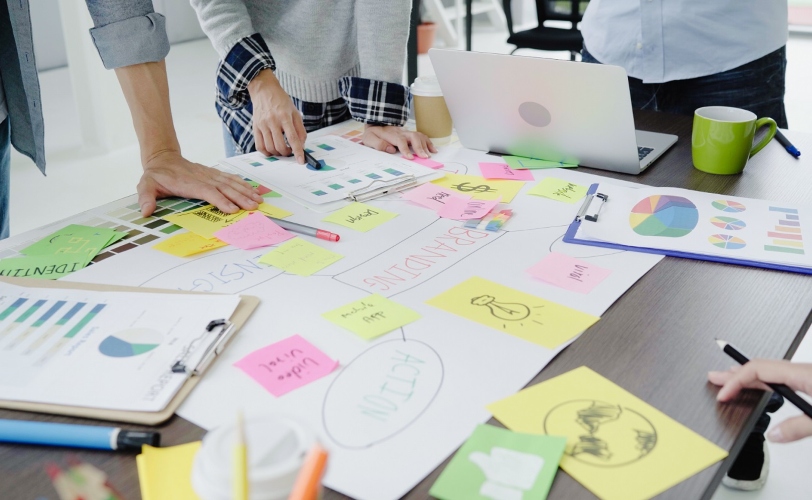 imagem mostra uma mesa com várias pessoas em volta, reunidas para fazerem a análise SWOT de uma empresa.