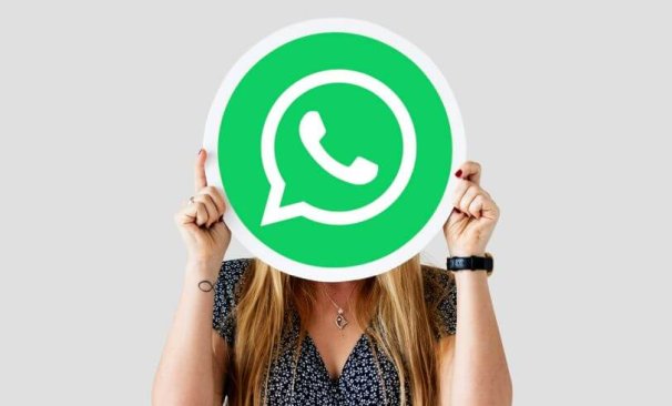 Alt text: na imagem há uma mulher com o logo do WhatsApp em frente ao seu rosto. A imagem faz referência ao conteúdo de botão do whatsapp em sites de ecommerce.