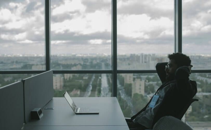 Na imagem está um homem sentado na mesa de um escritório.