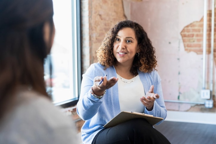 A imagem mostra uma mulher falando e gesticulando com outra. A imagem transpassa empatia, tema abordado no conteúdo em texto. 