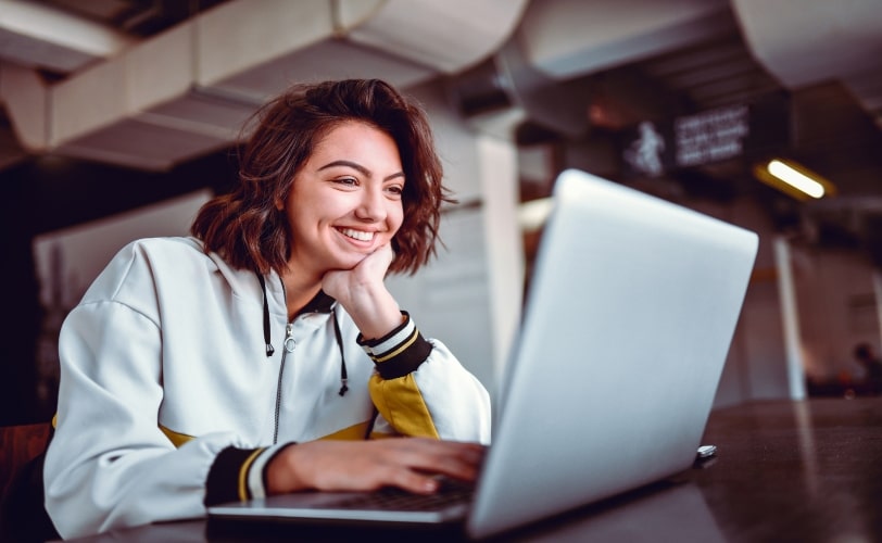 Mulher sorrindo e olhando para um notebook