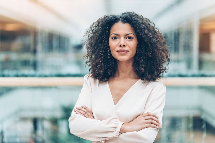 A imagem mostra uma mulher de braços cruzados. Ela está no que parece ser um escritório. Ela tem um olhar firme e decidido, característico de pessoas que sabem aplicar bem os conceitos do marketing pessoal. 