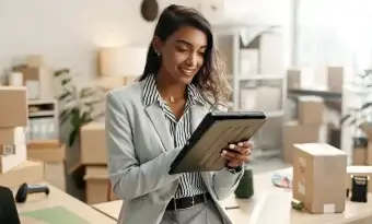 A imagem mostra uma mulher no que parece ser o armazém de uma loja online. Há várias caixas organizadas, indicando possíveis vendas que ela fez durante a Black Friday.