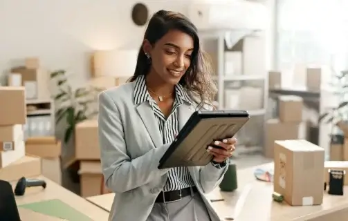 A imagem mostra uma mulher no que parece ser o armazém de uma loja online. Há várias caixas organizadas, indicando possíveis vendas que ela fez durante a Black Friday.