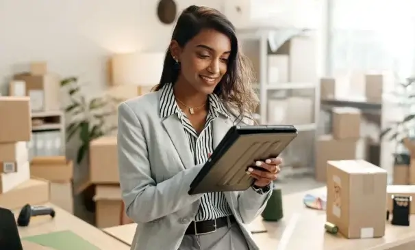 A imagem mostra uma mulher no que parece ser o armazém de uma loja online. Há várias caixas organizadas, indicando possíveis vendas que ela fez durante a Black Friday.