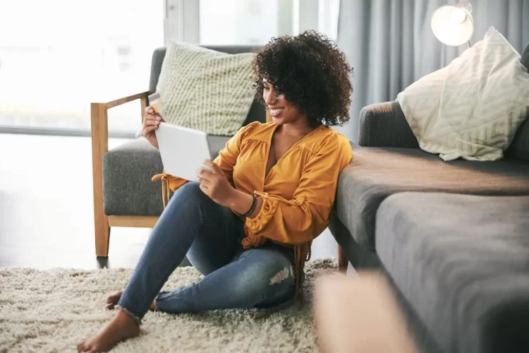 A imagem mostra uma mulher negra usando um tablet para fazer uma compra online. Ela está segurando um cartão de crédito, o que pode indicar que está fechando uma compra durante o período da Black Friday. 