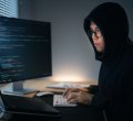 homem no computador escrevendo código malicioso