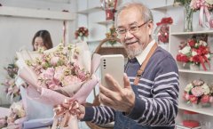 Vendedor asiático fazendo selfie de um buquê de flores em uma loja.