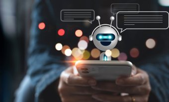 A imagem mostra uma pessoa digitando em um celular para interagir com um robô. Ele aparece saindo da tela, indicando que uma conversa está em andamento.