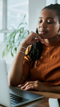 A imagem mostra uma mulher negra em um escritório com uma expressão pensativa. Ela está avaliando como aplicar os recursos da CDN para melhorar o desempenho do site de sua empresa.