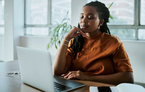 A imagem mostra uma mulher negra em um escritório com uma expressão pensativa. Ela está avaliando como aplicar os recursos da CDN para melhorar o desempenho do site de sua empresa.
