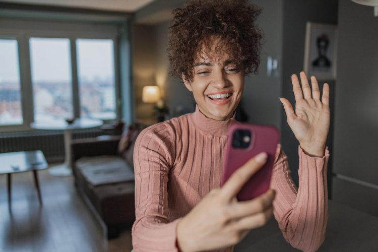 A imagem mostra uma moça jovem gravando um vídeo com o celular na sala da casa dela. Esse material possivelmente será publicado em uma rede social como o TikTok, e depois terá algum tipo de impulso com o auxílio do TikTok Ads. 