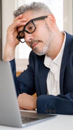 A imagem mostra um homem com expressão preocupada olhando para o notebook. Ele provavelmente está assim pelo fato de a página dele ter entrado em uma lista de sites ruins.