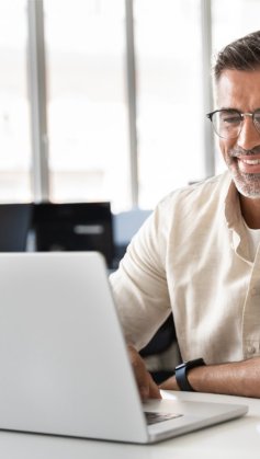 A imagem mostra um homem de meia-idade em um escritório digitando em um notebook. Ele possivelmente está analisando um slug que foi criado para a publicação de um post em seu blog.