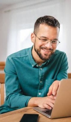 A imagem mostra um homem trabalhando em um notebook. Ele está no que parece ser a cozinha de um escritório e, possivelmente, está realizando uma busca para saber como descobrir a fonte de uma imagem na internet.